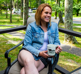 A happy guest drinking coffee on her porch at Lewis Mountain Cabins